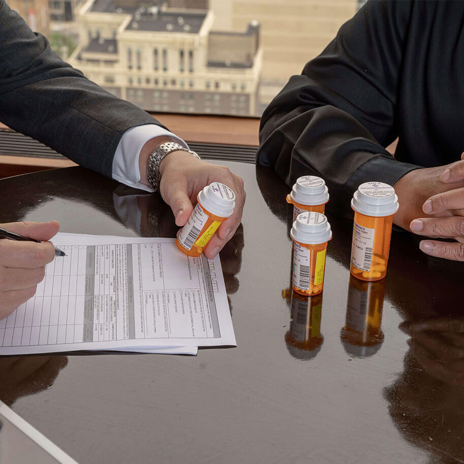 Close-up of HNB attorney Mike Rake holding a prescription bottle in his hand while meeting a client. Our attorneys make the process of applying for Social Security Disability benefits as easy as possible for you.