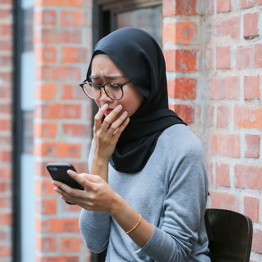 A woman wearing a hijab shows concern while she looks at her smartphone. The Ohio wrongful termination religious discrimination lawyers at Horenstein, Nicholson & Blumenthal know how to identify employer misbehavior.