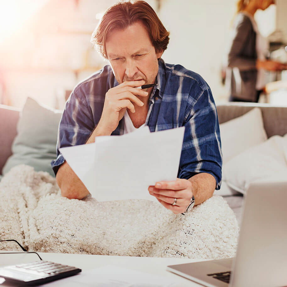A man sits on a couch looking over papers and a computer. The Ohio wrongful termination age discrimination lawyers at Horenstein, Nicholson & Blumenthal can guide you through a legal claim.