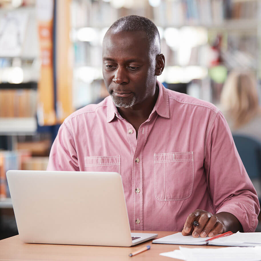 A man sits at a laptop computer in a library. The Ohio wrongful termination race discrimination lawyers at Horenstein, Nicholson & Blumenthal can guide you through your legal claim.