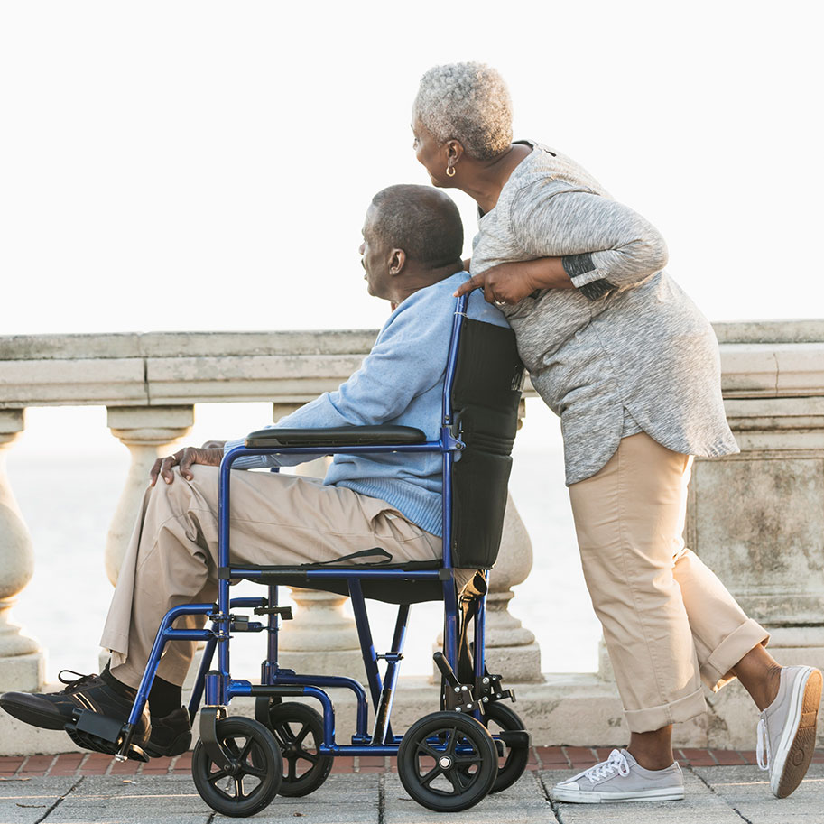 A woman pushes a man in a wheelchair on a bridge. Get an HNB attorney to help you win monthly SSI benefits when you can’t work because of a disablity.