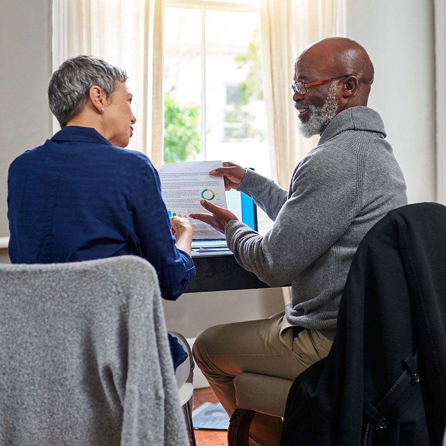 A couple looks at papers at a table in front of a window. HNB can help you determine if you can speed up your cancer disability benefits.