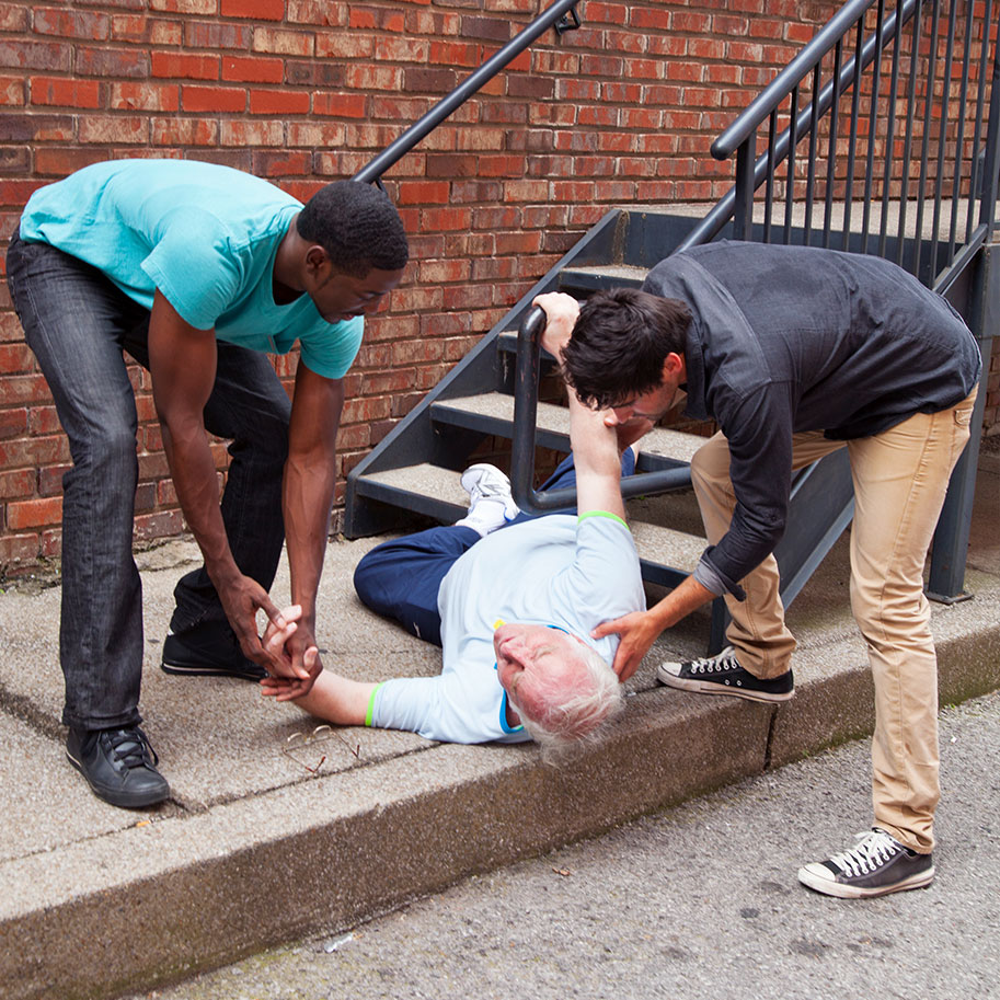 Two men help a man lying at the bottom of a set of stairs. Horenstein, Nicholson & Blumenthal lawyers can help you after multiple kinds of injuries on private property.