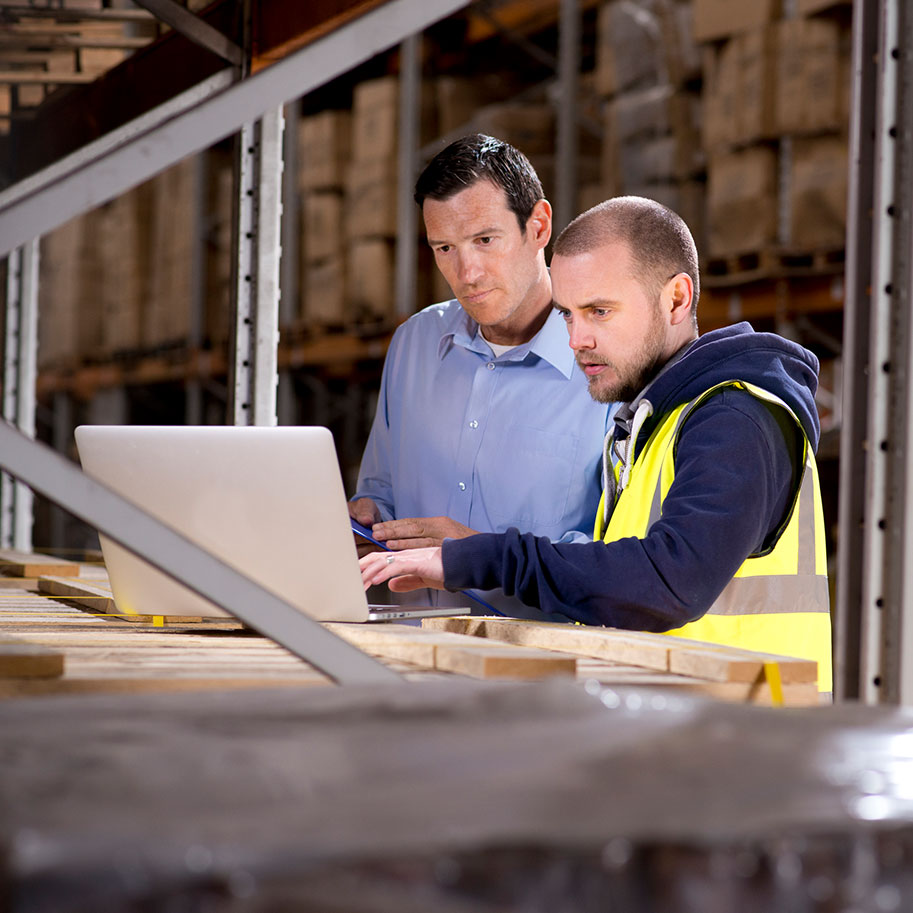 Two men look at a laptop on a shelf in a warehouse. The warehouse employees’ workers’ compensation lawyers at Horenstein, Nicholson & Blumenthal help you navigate the benefits system.