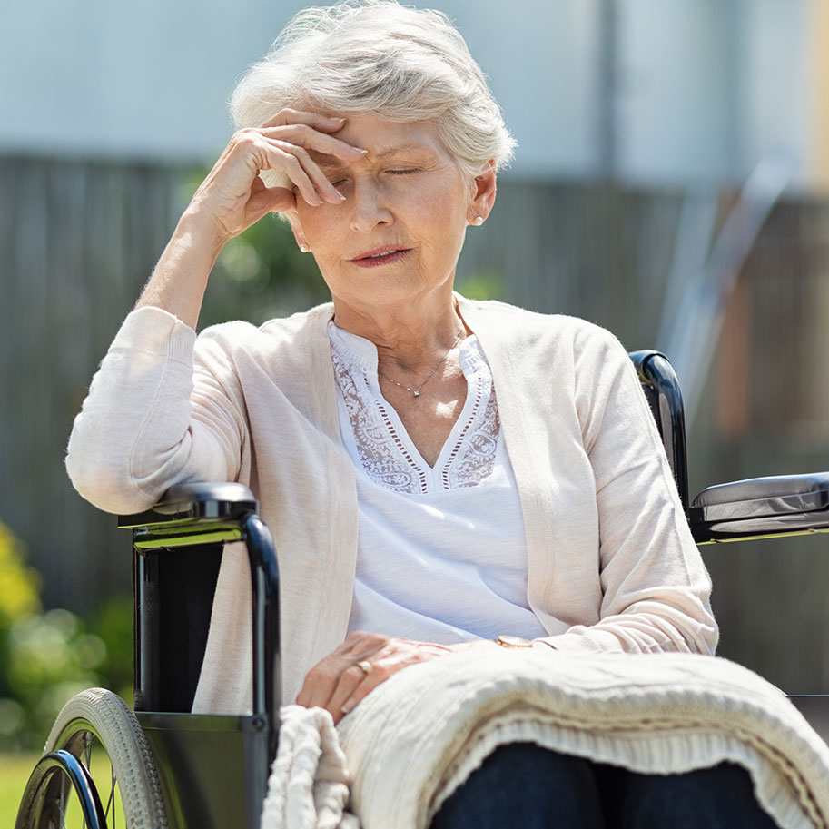 A woman sits in a wheelchair on a lawn, resting her forehead in one hand. The Ohio nursing home negligence lawyers at HNB can identify the signs of bad treatment that may give your family a legal claim.