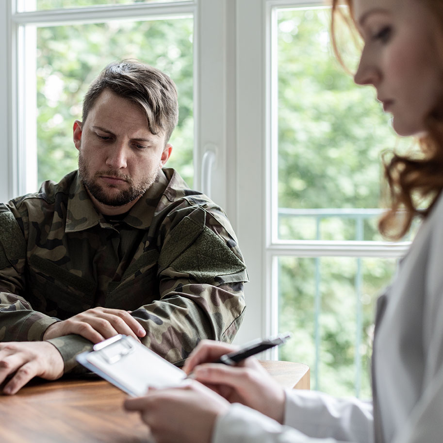 A man in military fatigues looks down at a table while meeting with a doctor. Get Horenstein, Nicholson & Blumenthal’s PTSD lawyers to deal with the VA disability benefits system, so you can focus on managing your PTSD.