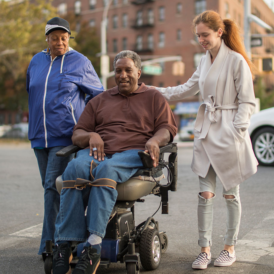 A man in a motorized wheelchair on a city street with two people walking next to him. Even if you could work for a long time, Horenstein, Nicholson & Blumenthal can help you qualify for total disability individual unemployability when your condition worsens.