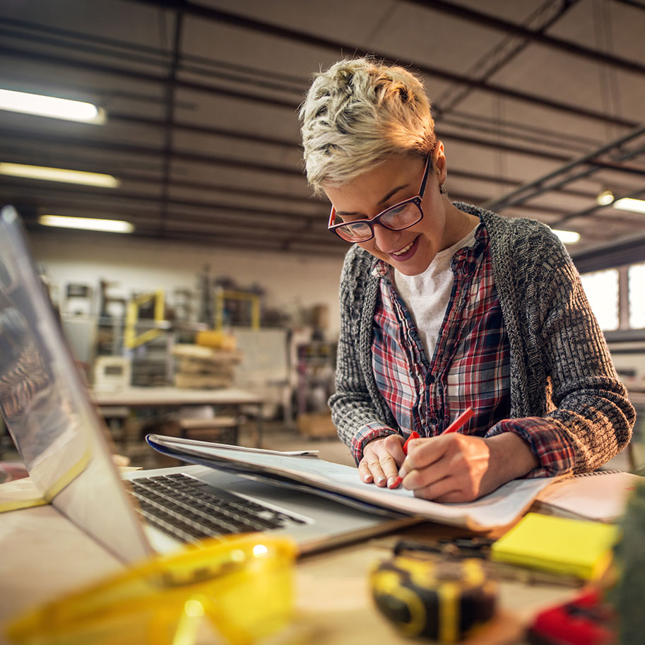 A woman writes in a notebook in an industrial shop. When you need workers’ compensation for joint injuries, Horenstein, Nicholson & Blumenthal attorneys help you through the process.