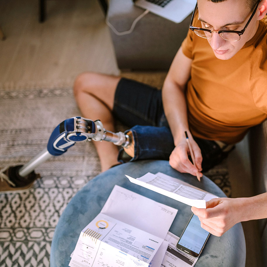 A man with a prosthetic leg sits on the floor of his home, looking at papers on a stool. When you need workers’ compensation for a loss of limb/amputation, Horenstein, Nicholson & Blumenthal attorneys help you through the process.